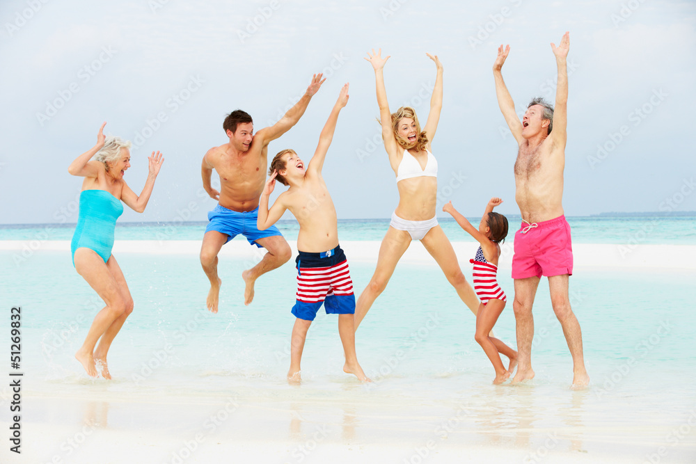 Multi Generation Family Having Fun In Sea On Beach Holiday