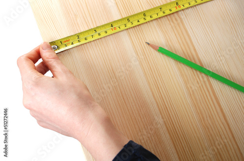 Using a steel tape measure on a wooden board against a white bac