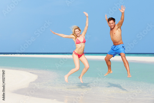 Couple Jumping On Beautiful Tropical Beach
