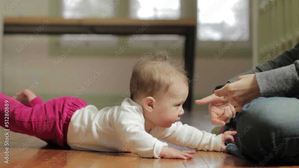 Mother helping baby stand up from the floor Mother helping baby stand up from the floor