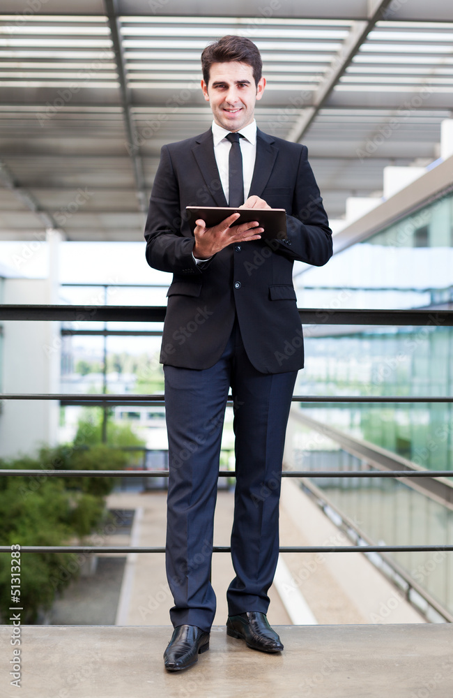 Smiling young businessman using his digital tablet at the office Smiling young businessman using his digital tablet at the office