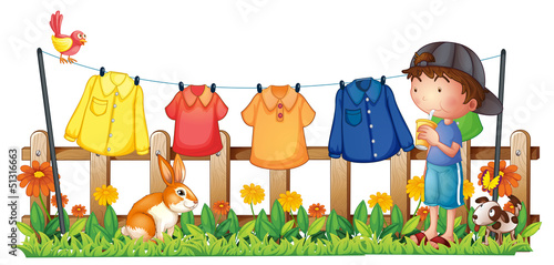 A boy drinking in the garden with hanging clothes