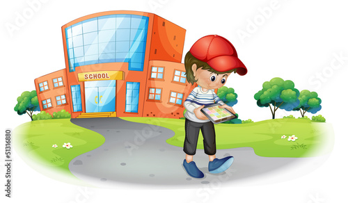 A boy holding a gadget near the school