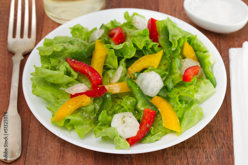 fresh salad on white plate with glass of white wine