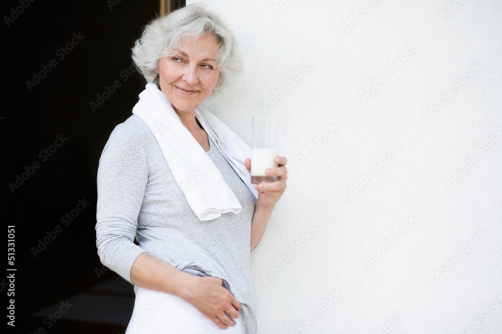 grauhaarige Frau nach dem Workout mit einem Glas Milch grauhaarige Frau nach dem Workout mit einem Glas Milch
