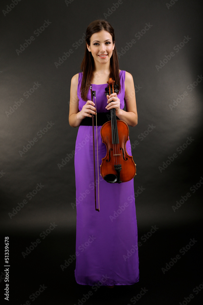 Obraz premium Young female musician in elegant purple gown holding violin and bow, classical music performance and artistic talent, violinist