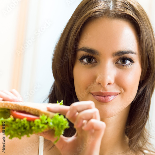 Happy smiling woman with sandwich at home