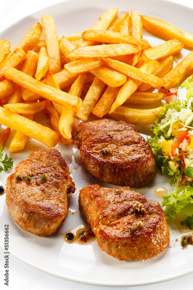Grilled steaks, French fries and vegetables Grilled steaks, French fries and vegetables