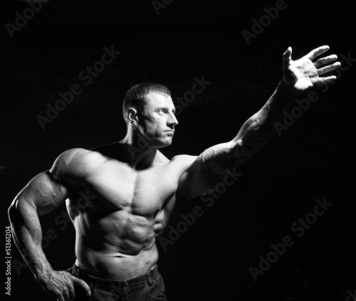 shirtless muscle man is posing on a dark background