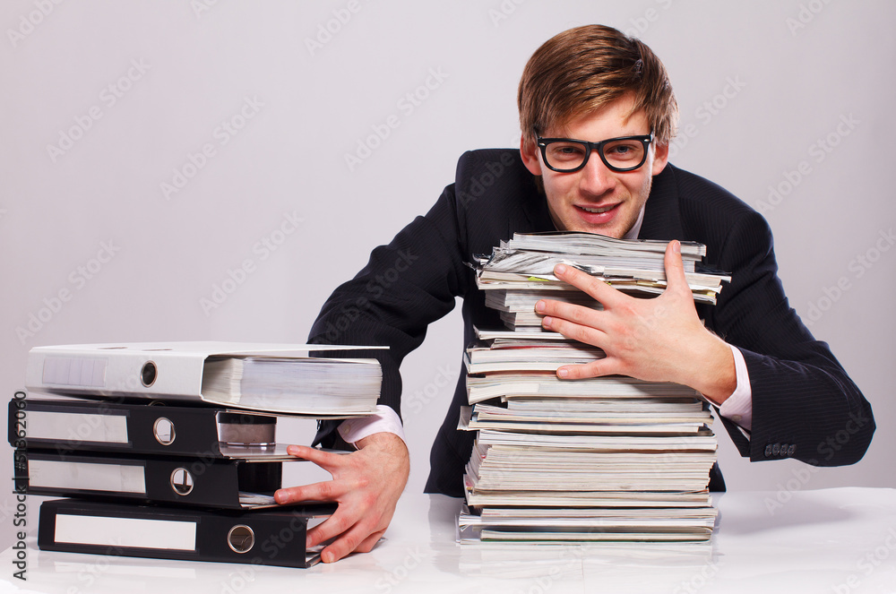 young man is sitting in the office and holding some folders and