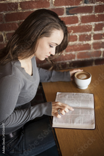 Young Woman with White Coffee Cup Reads Her Bible