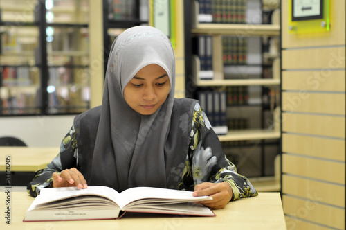 Young Muslim student studying in the library
