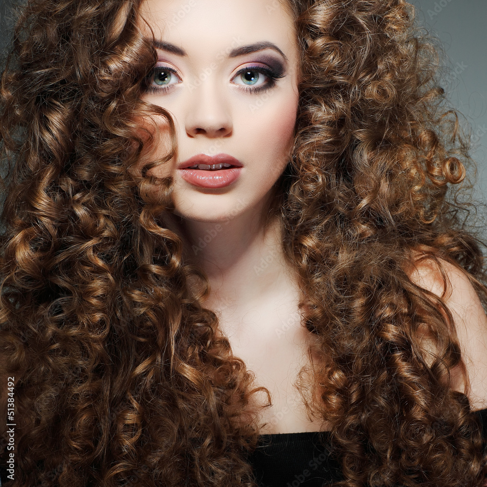 Fototapeta premium Young beautiful woman with long curly hairs