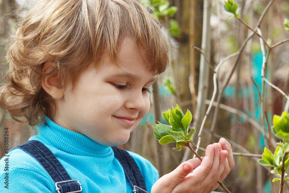 Little blond boy holding the bloom leaves outdoors Little blond boy holding the bloom leaves outdoors