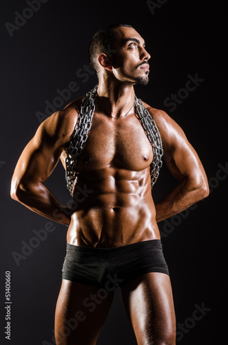 Muscular man with chain on black background