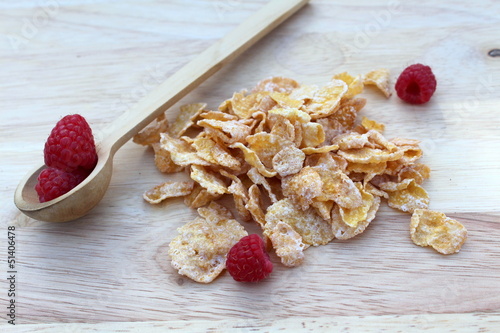 Fresh raspberries and frosted cereal on wood board