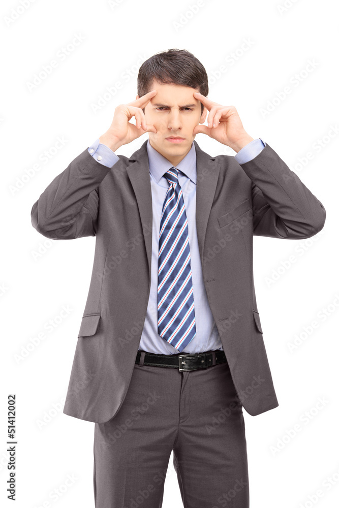 A young businessman holding his head in pain as a result of a he A young businessman holding his head in pain as a result of a he