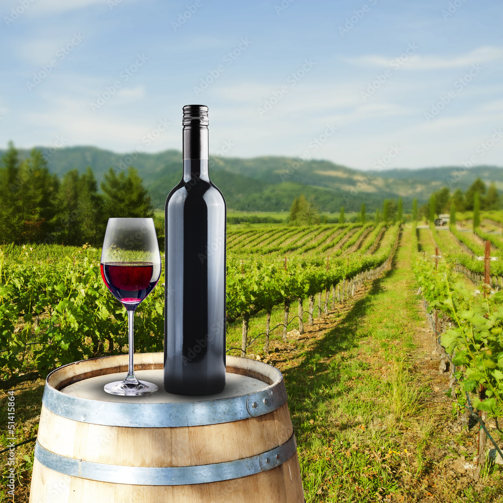 Poster encadré Verre et bouteille de vin rouge sur tonneau en bois avec  scène de vignoble 