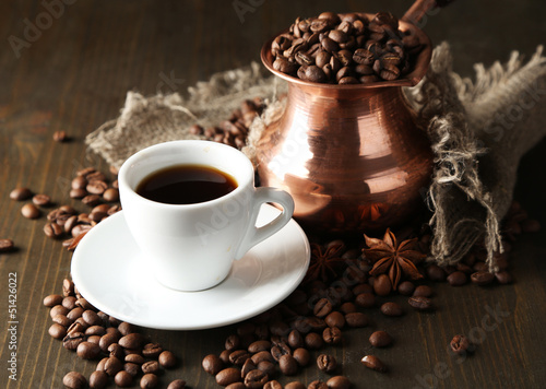 Cup of coffee and pot on wooden background