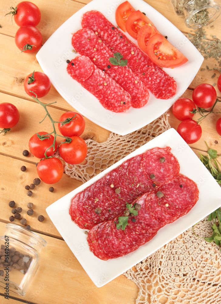 Tasty salami on plates on wooden table close-up Tasty salami on plates on wooden table close-up
