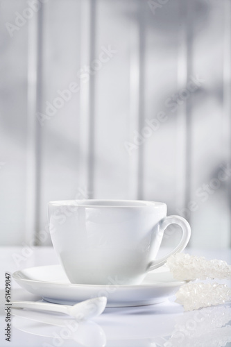 white ceramic coffee cup with spoon and sugar sticks