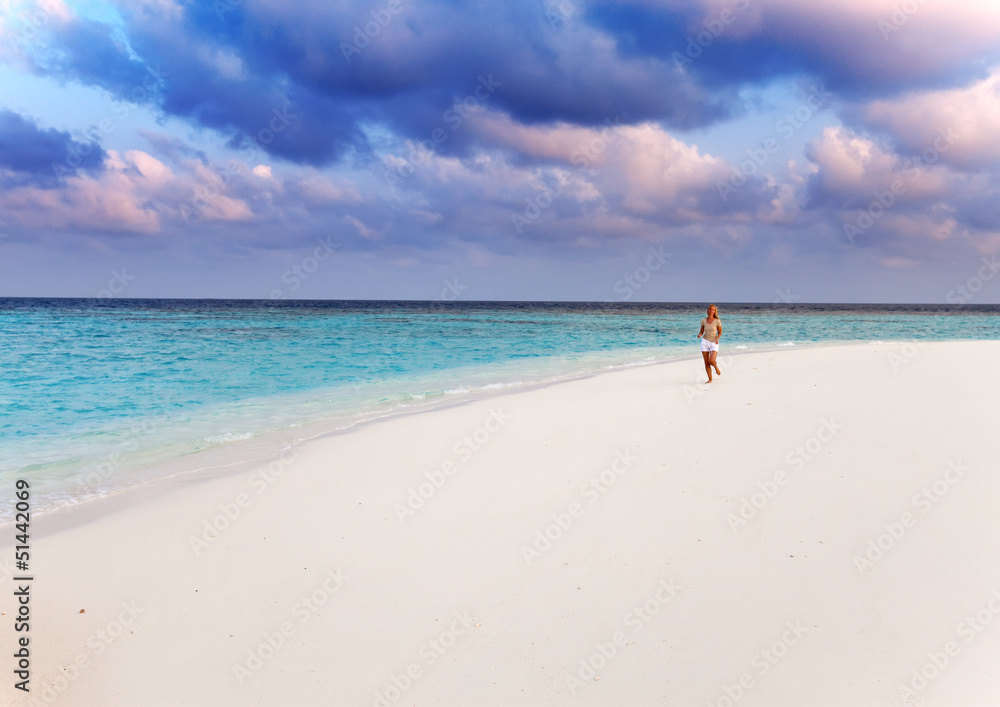 The sporting woman runs on the seashore. Maldives
