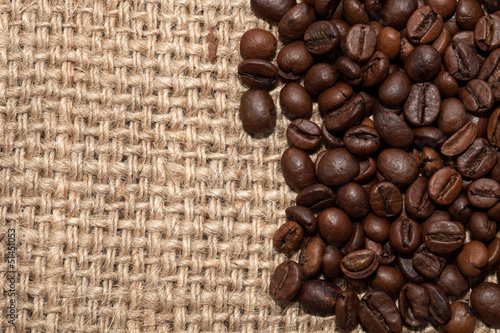Coffee grains on rough fabric of linen close-up