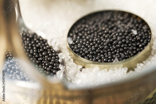 Black caviar in small round metal tin on ice photo