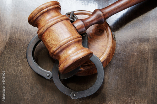 Gavel and handcuffs on wooden background