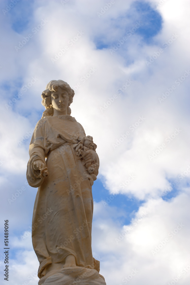 Angelic Statue with fluffy blue clouds and sky.