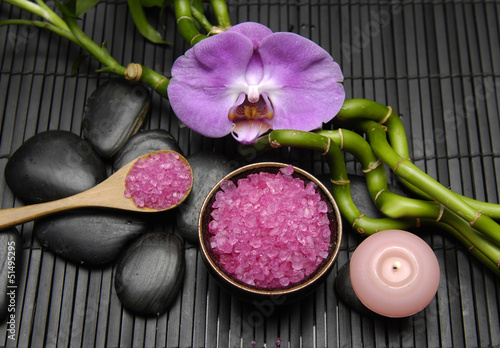 Pink salt in spoon with orchid and bamboo grove on mat