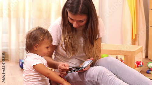Education: mother reading book to small girl at home