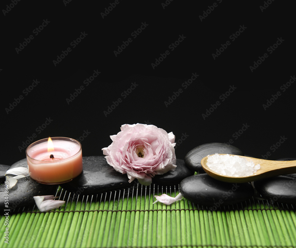 Pink ranunculus with candle ans salt in spoon on green mat