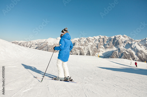 Ski woman in snow mountain landscape with blue sky. photo
