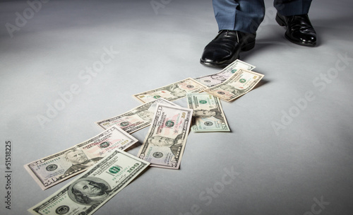 Men's feet and dollar banknotes on the floor