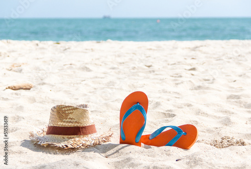 flip-flop and a woven hat on the beach.