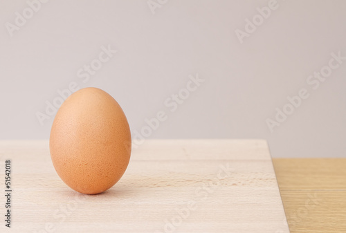 Single brown egg on wooden chopping block