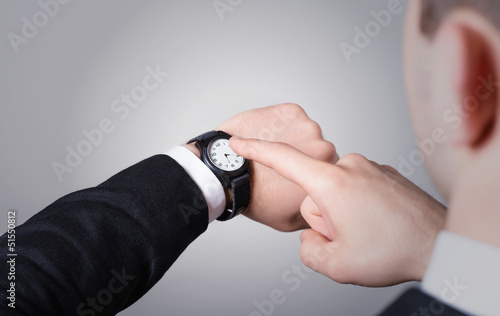 Man's hand in the suit pointing on his watch
