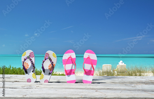 Two pairs of flip-flops against ocean. Exuma, Bahamas