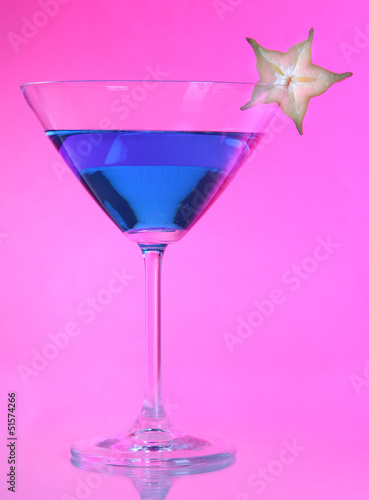 Blue cocktail in martini glass on pink background