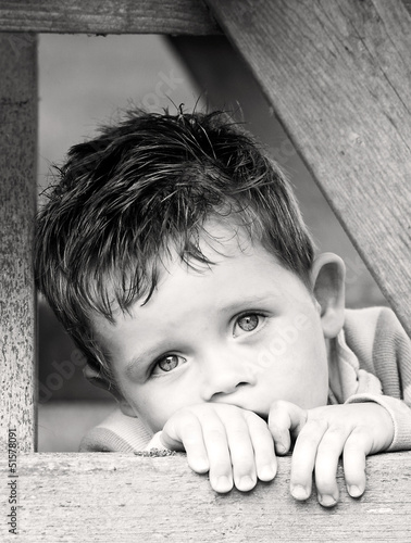 sad depressed little boy peering from beyond his hands