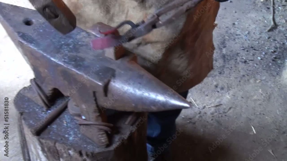 Blacksmith is hammering red-hot piece of iron Blacksmith is hammering red-hot piece of iron