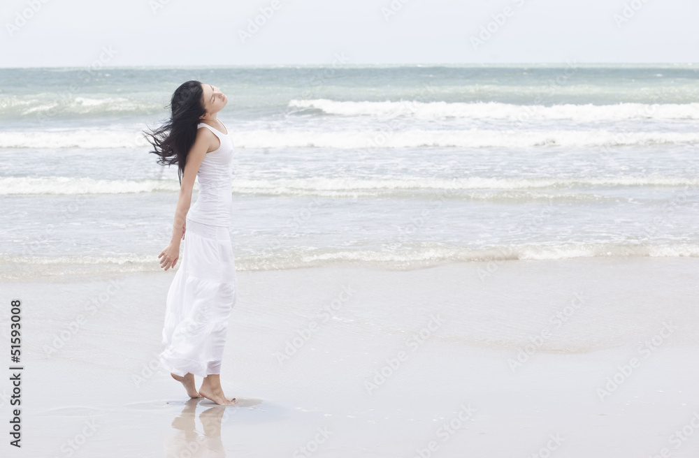 The woman in a white sundress on seacoast with open hands The woman in a white sundress on seacoast with open hands