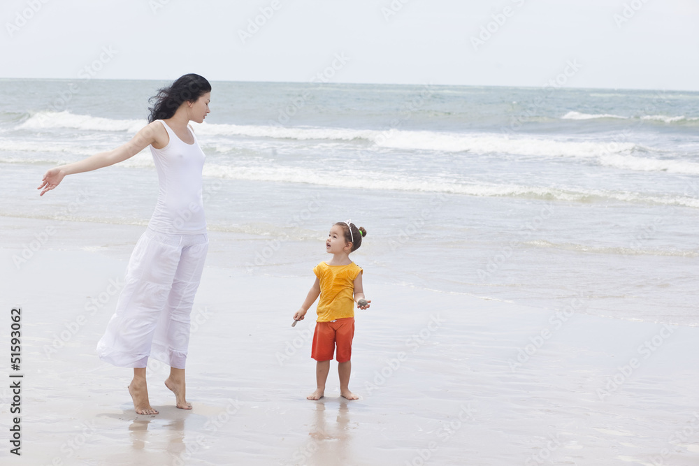 Mother and daughter walking along tropical beach