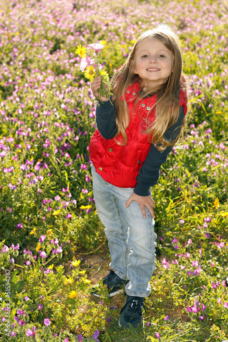 Bambina sorridente in piedi raccoglie i fiori