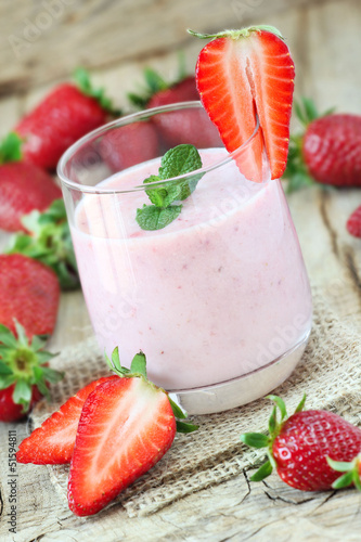 Strawberrie smoothie with fresh strawberries at the background