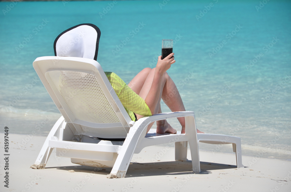 Girl with a glass of soda on the tropical beach