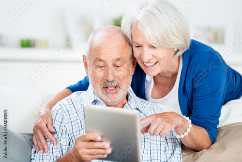 lachendes senioren-paar mit tablet