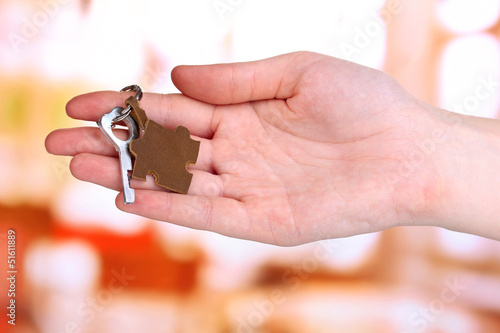 Key with leather trinket in hand on bright background