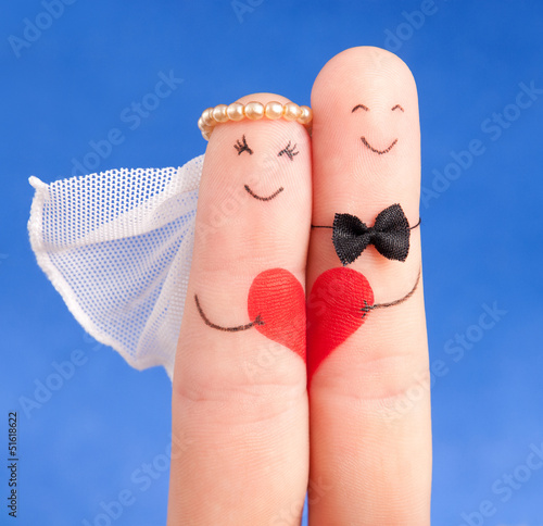 wedding concept -  newlyweds painted at fingers against blue sky photo